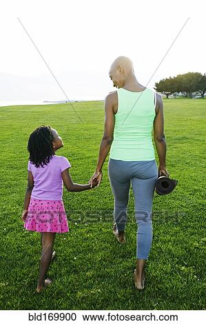 Stock Image - Mother and daughter holding hands in park. Fotosearch