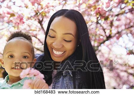 Stock Image - Mother and daughter under flowering tree in park. Fotosearch