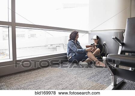 Stock Photo - Mother and son using digital tablet in airport. Fotosearch