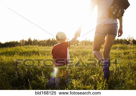 Stock Photography - Mother and son walking in rural field. Fotosearch