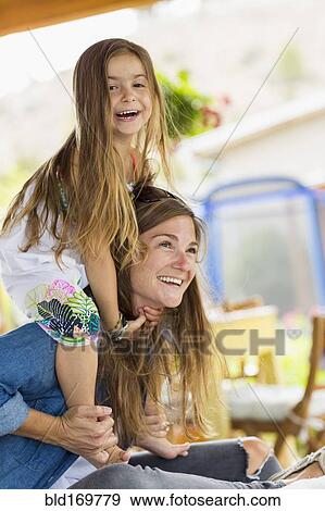 Mother carrying daughter on shoulders View Large Photo Image Stock Photo - Mother carrying daughter on shoulders. Fotosearch