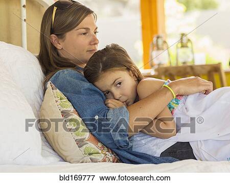 Mother comforting sad daughter on bed View Large Photo Image Stock Photo - Mother comforting sad daughter on bed. Fotosearch