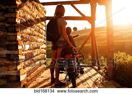Picture - Mother holding son on motorcycle on patio. Fotosearch