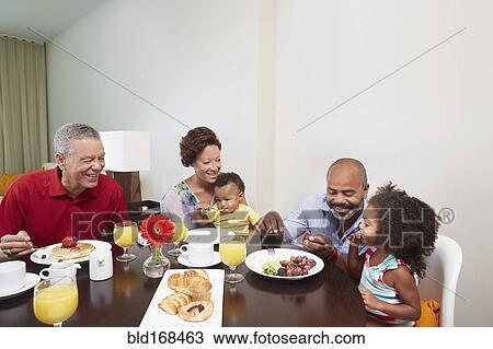 Stock Image - Multi-generation family eating breakfast at table. Fotosearch