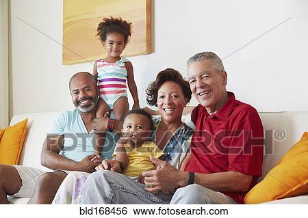 Stock Photograph - Multi-generation family smiling on sofa. Fotosearch
