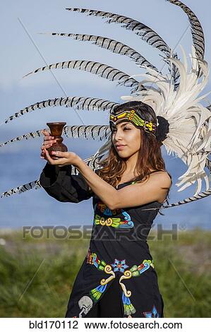 Stock Image - Native American woman in traditional headdress performing ceremony. Fotosearch
