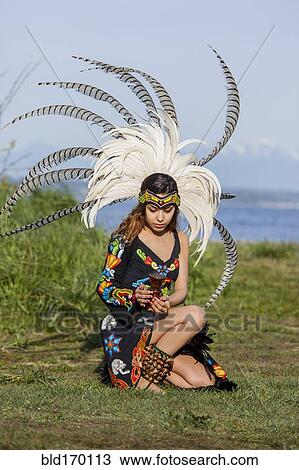Stock Image - Native American woman in traditional headdress performing ceremony. Fotosearch