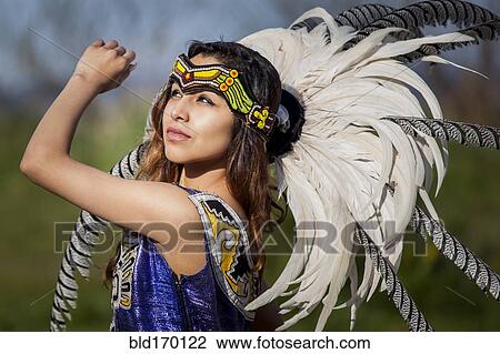 Stock Image - Native American woman in traditional headdress performing ceremony. Fotosearch