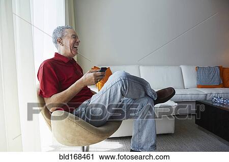 Older Black man using cell phone in living room View Large Photo Image Stock Image - Older Black man using cell phone in living room. Fotosearch