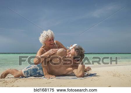 Stock Photography - Older Caucasian couple relaxing on beach. Fotosearch