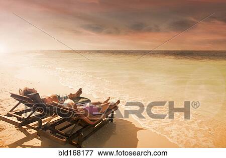 Older Caucasian couple relaxing on beach at sunset View Large Photo Image Stock Photo - Older Caucasian couple relaxing on beach at sunset. Fotosearch