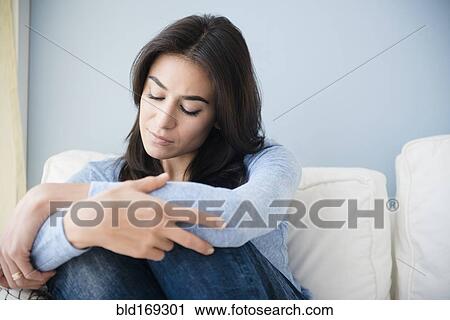 Stock Image - Sad woman sitting on sofa. Fotosearch