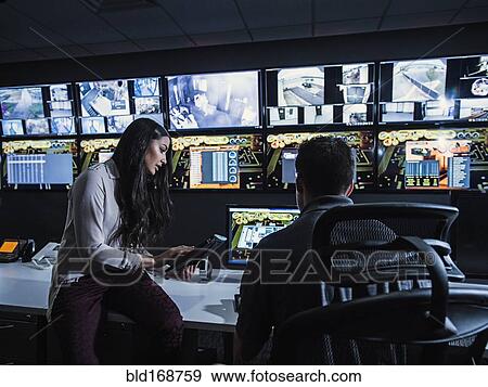 Stock Photo - Security guards watching monitors in control room. Fotosearch