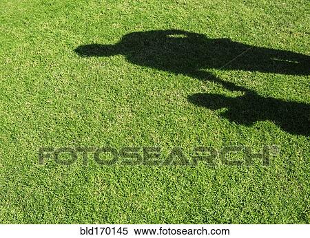 Stock Photography - Shadow of Hispanic father and son on grass lawn. Fotosearch