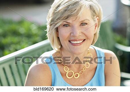 Smiling Caucasian woman sitting on bench View Large Photo Image Stock Image - Smiling Caucasian woman sitting on bench. Fotosearch