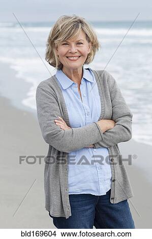 Picture - Smiling Caucasian woman standing on beach. Fotosearch