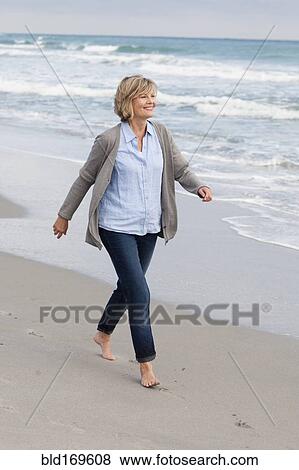 Smiling Caucasian woman walking on beach View Large Photo Image Stock Photo - Smiling Caucasian woman walking on beach. Fotosearch