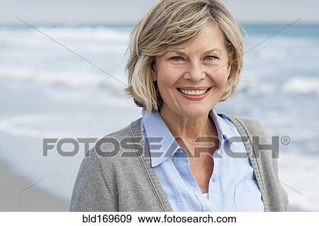 Stock Photo - Smiling Caucasian woman walking on beach. Fotosearch