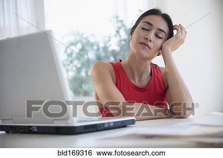 Stressed businesswoman sitting at laptop at desk View Large Photo Image Stock Photograph - Stressed businesswoman sitting at laptop at desk. Fotosearch