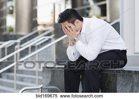 Stock Photography - Stressed mixed race businessman covering his face. Fotosearch
