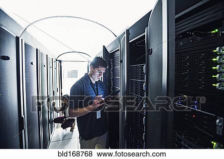 Stock Photo - Technician using digital tablet in server room. Fotosearch