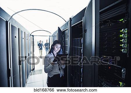 Stock Photograph - Technician using digital tablet in server room. Fotosearch