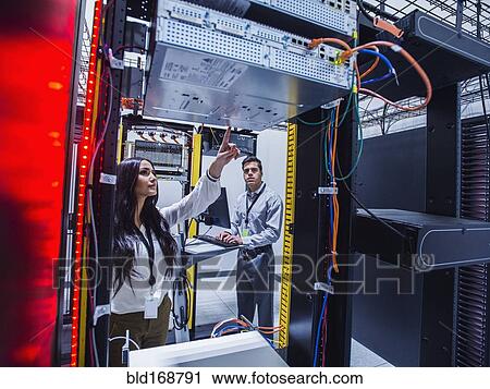 Stock Image - Technicians examining computer in server room. Fotosearch