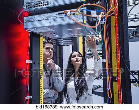 Stock Photo - Technicians examining computer in server room. Fotosearch