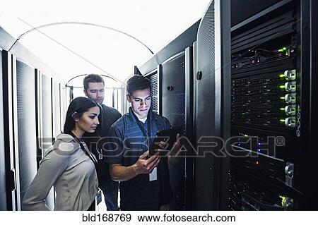 Stock Photo - Technicians using digital tablet in server room. Fotosearch
