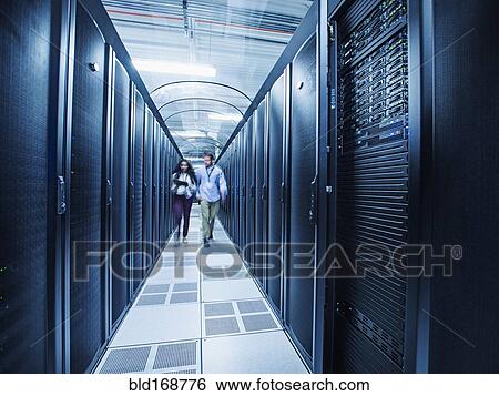 Stock Photograph - Technicians walking in server room. Fotosearch