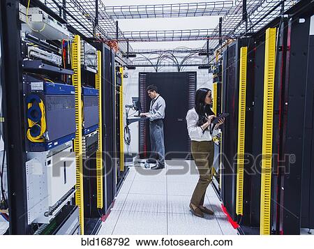 Stock Image - Technicians working in server room. Fotosearch