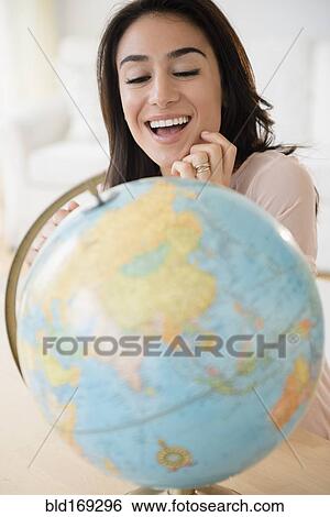Stock Photograph - Woman admiring globe on desk. Fotosearch