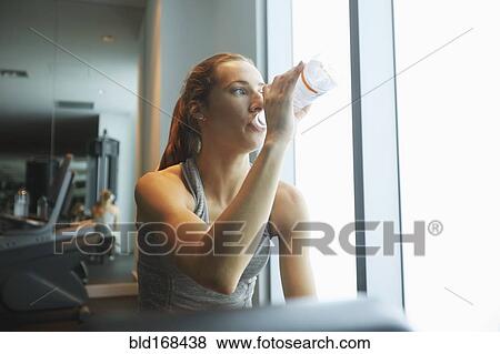 Woman drinking water bottle in gym View Large Photo Image Stock Photo - Woman drinking water bottle in gym. Fotosearch