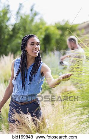 Stock Photo - Woman examining tall plants in garden. Fotosearch