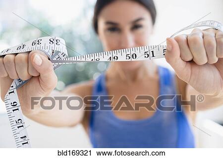 Stock Image - Woman holding measuring tape. Fotosearch