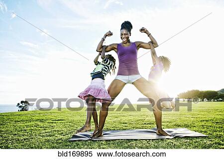 Stock Photography - Woman lifting children with biceps in park. Fotosearch
