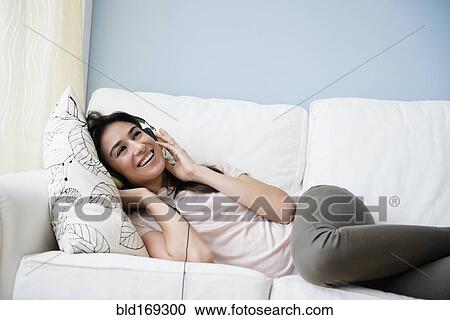 Woman listening to headphones on sofa View Large Photo Image Stock Image - Woman listening to headphones on sofa. Fotosearch