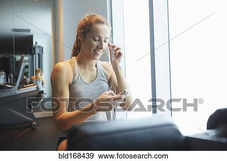 Stock Photo - Woman listening to mp3 player in gym. Fotosearch