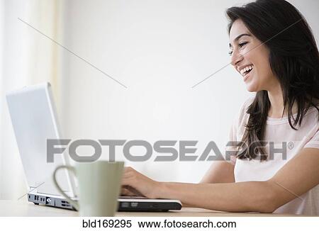 Stock Photography - Woman using laptop with cup of coffee. Fotosearch