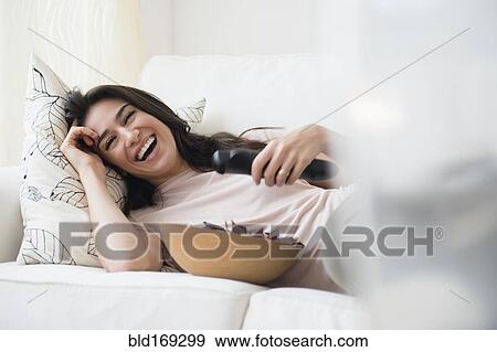 Stock Photo - Woman watching television on sofa. Fotosearch