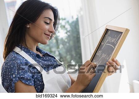 Woman writing specials on cafe chalkboard View Large Photo Image Picture - Woman writing specials on cafe chalkboard. Fotosearch