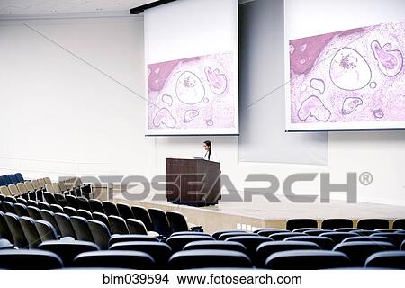 Picture - Armenian doctor speaking at podium in empty classroom. Fotosearch