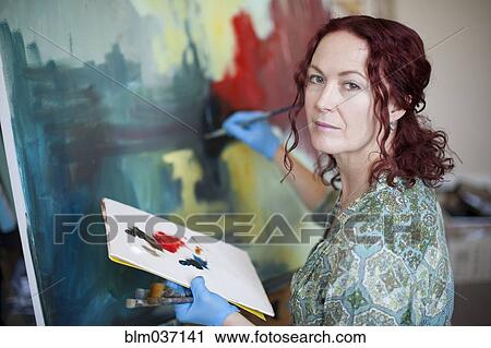 Stock Image - Artist painting on canvas in studio. Fotosearch