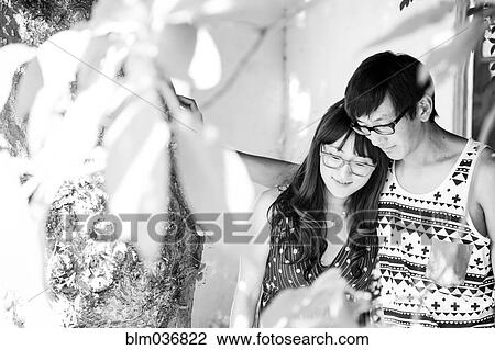 Stock Image - Asian couple standing in garden. Fotosearch
