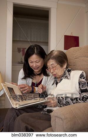 Stock Photo - Asian mother and daughter looking at photo album. Fotosearch