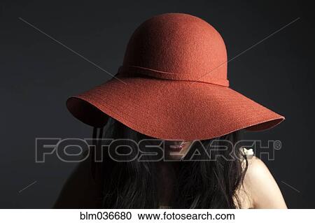 Stock Image - Asian woman hiding behind red hat. Fotosearch