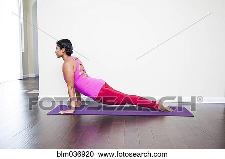 Stock Image - Asian woman practicing yoga in studio. Fotosearch