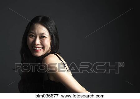 Asian woman smiling over her shoulder View Large Photo Image Stock Photo - Asian woman smiling over her shoulder. Fotosearch