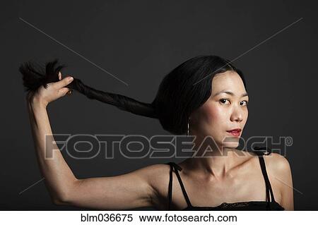 Stock Photography - Asian woman twisting her hair in ponytail. Fotosearch