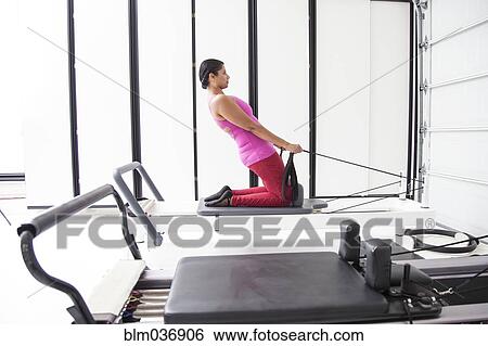 Stock Photograph - Asian woman using exercise machine in gymnasium. Fotosearch
